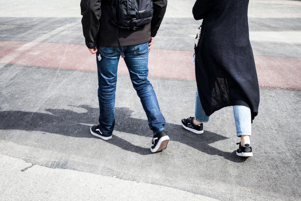 Kuva kävelevien nais- ja miesoletettujen jaloista.